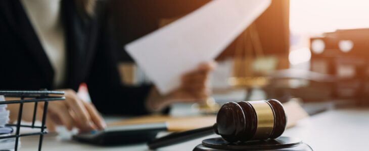 A female attorney reviews paperwork at her desk in front of a gavel resting on its stand.